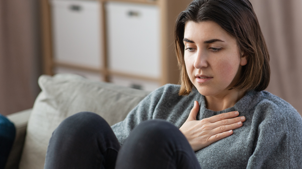 Woman sitting with hand over heart