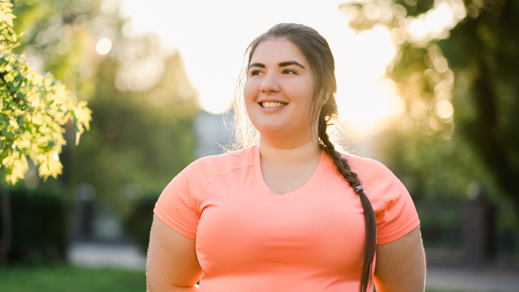 Woman with smile on her face and sun shining behind her